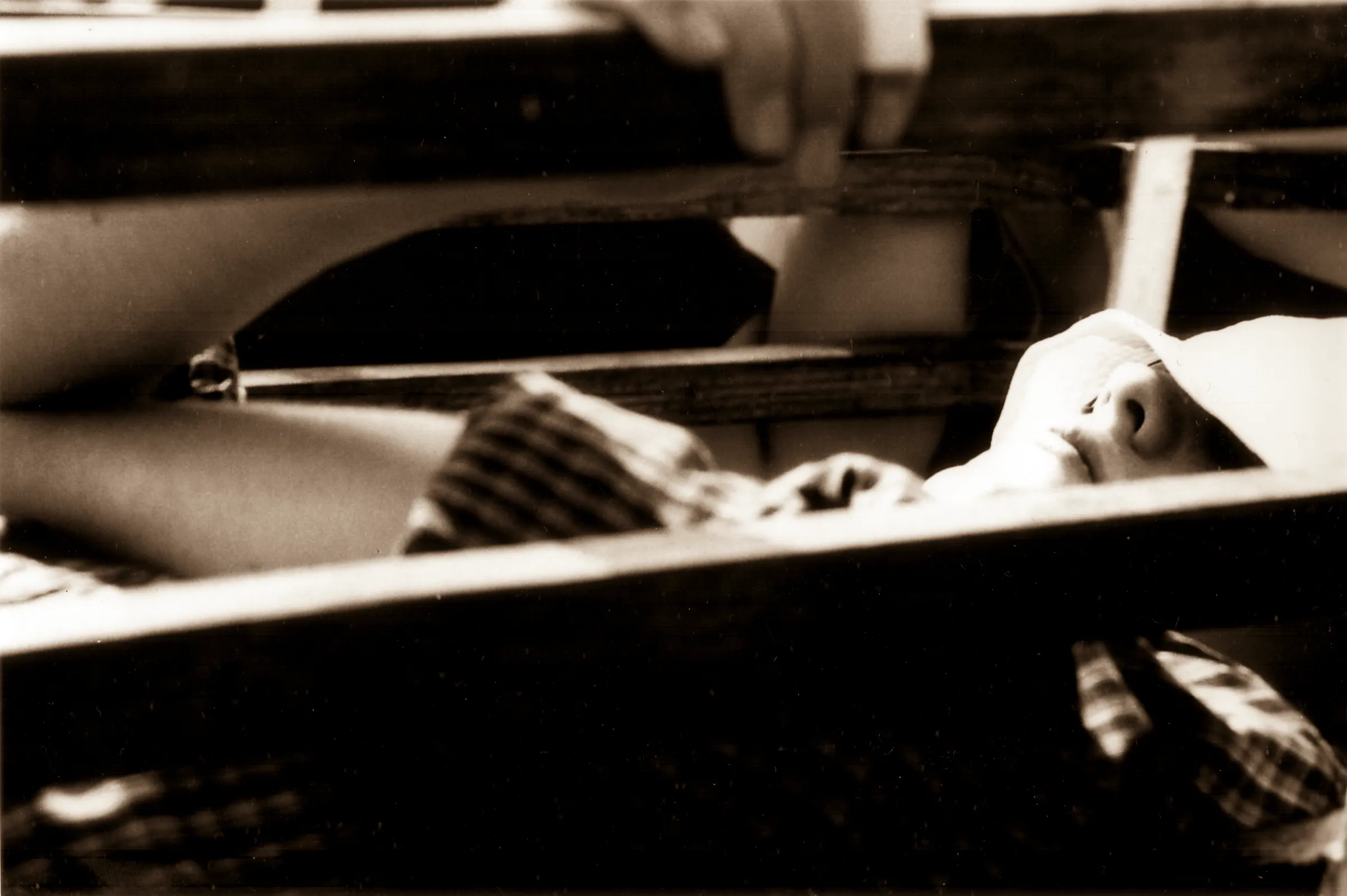 A baby lying in a crib with striped blanket, viewed from above.