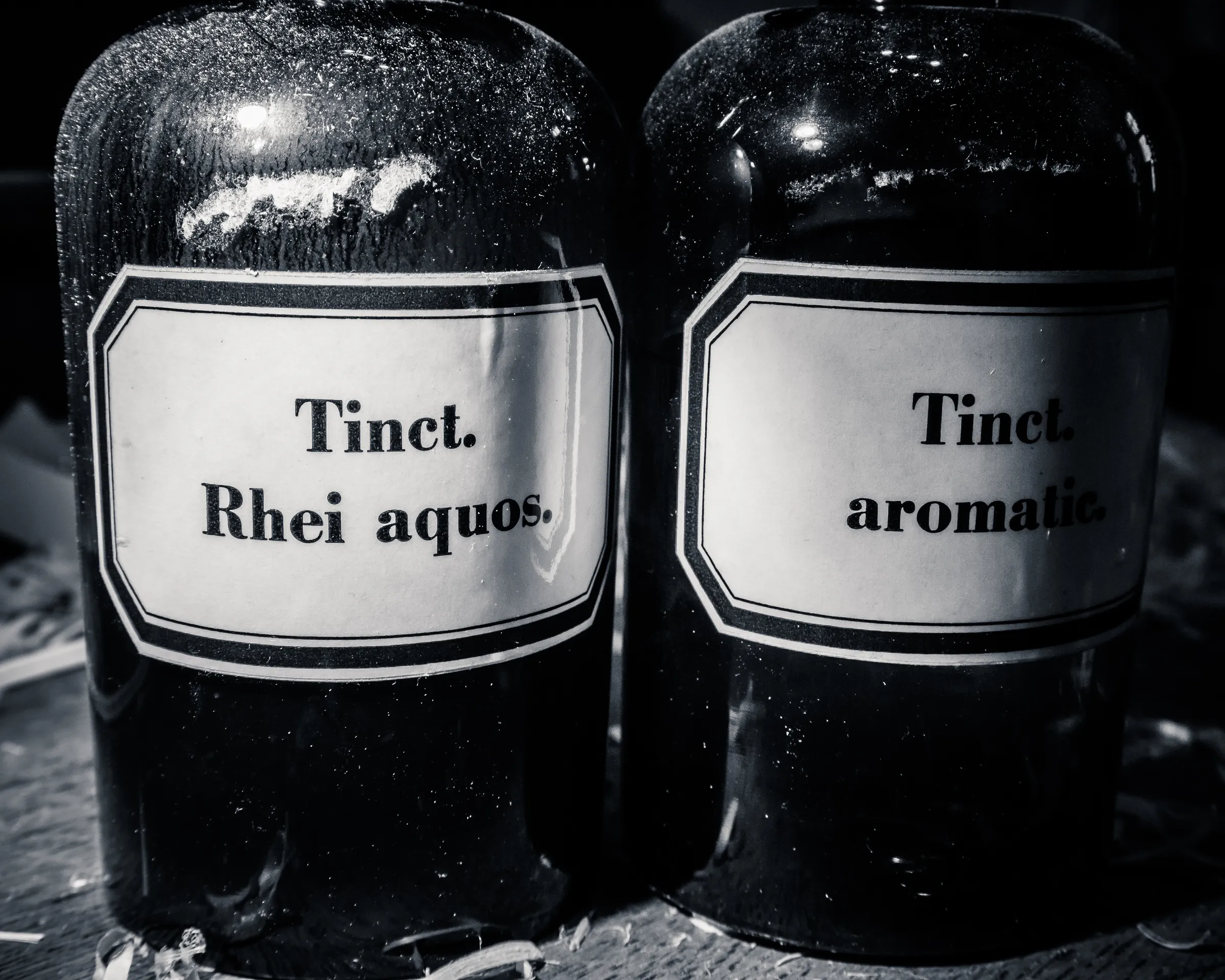 Two black bottles with white labels reading "Tinct. Rhei aquos." and "Tinct. aromatic."
