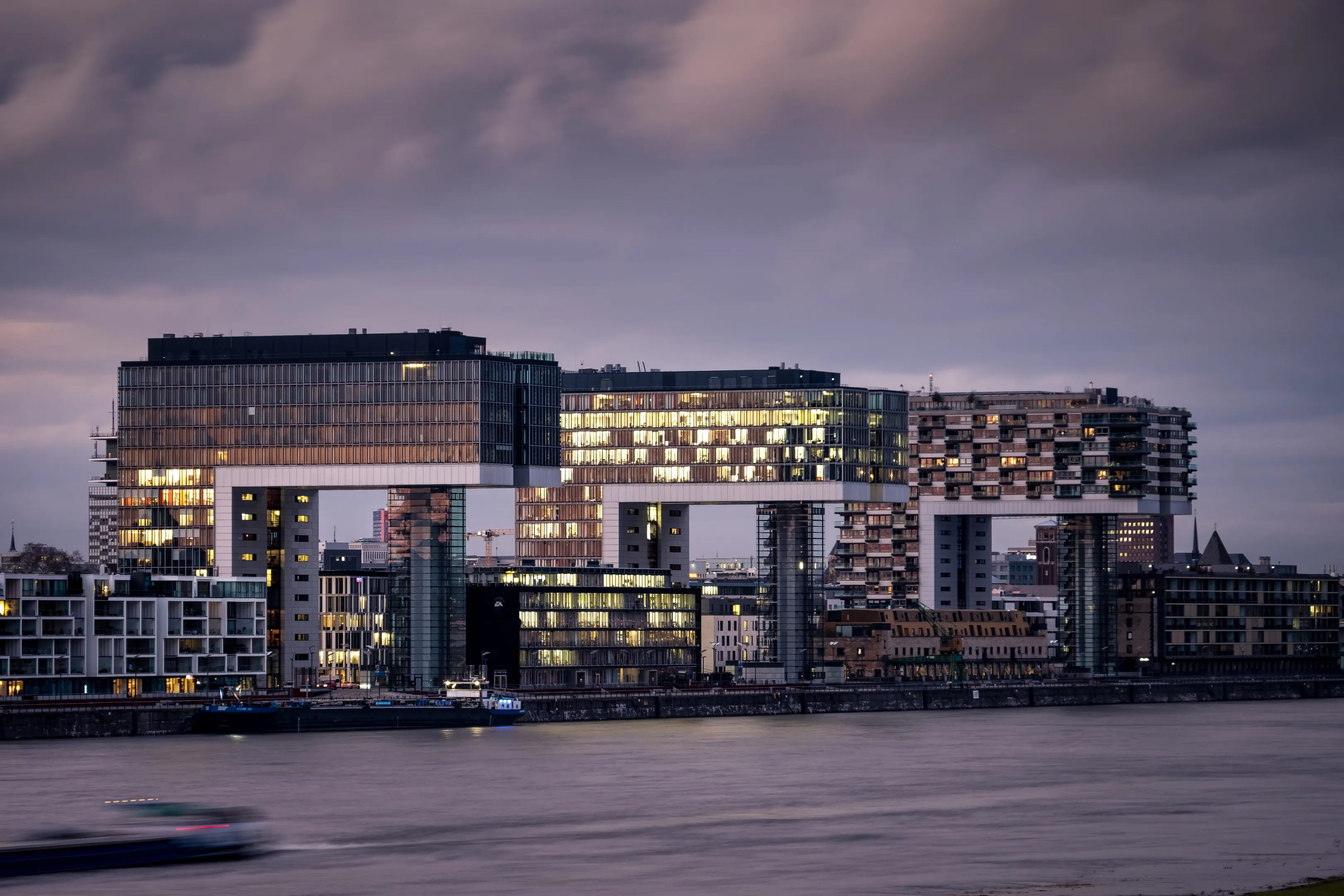 Modern architecture building at dusk with illuminated windows, reflected in calm water.