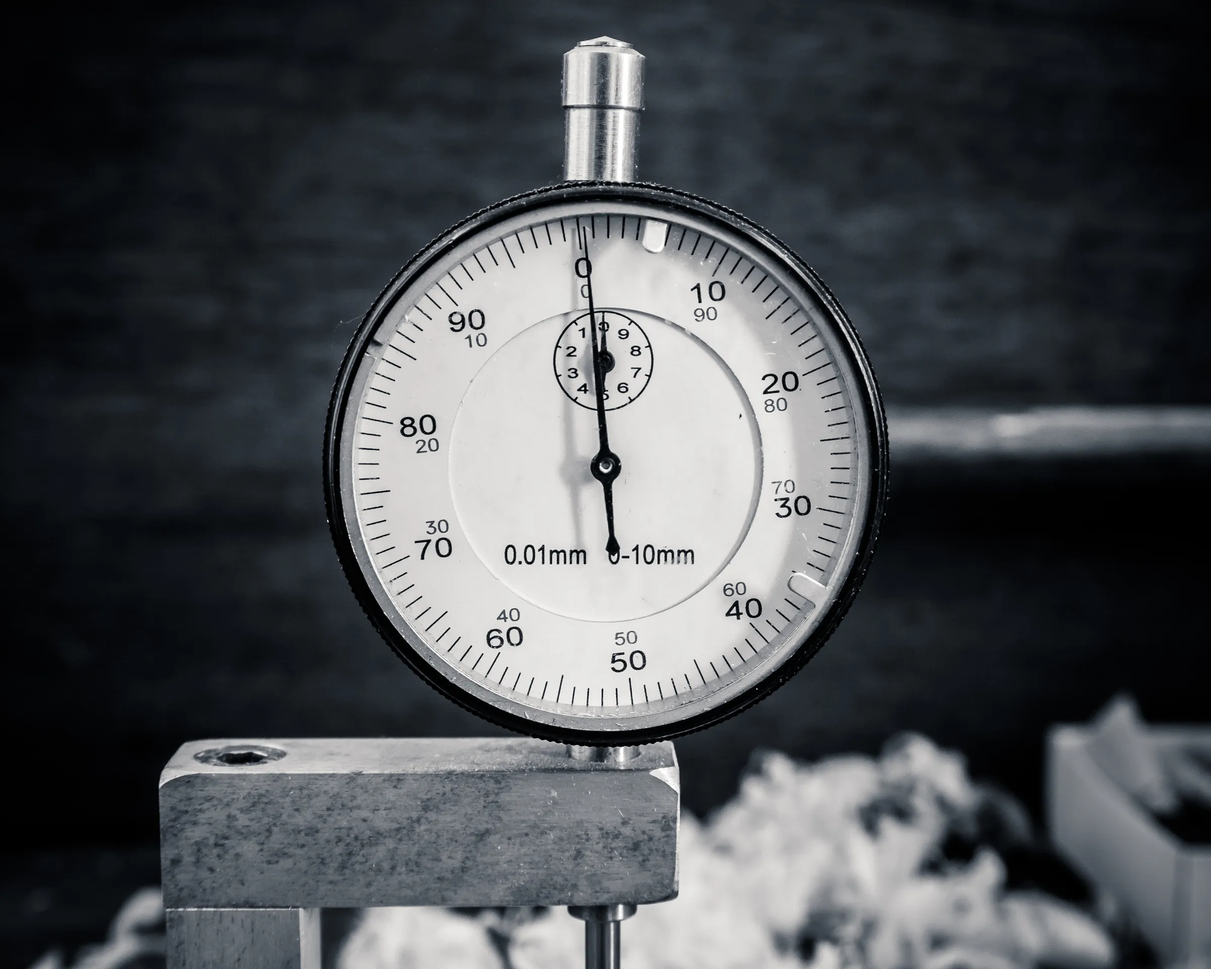 Close-up of a caliper measuring tool on a workshop surface, black and white.