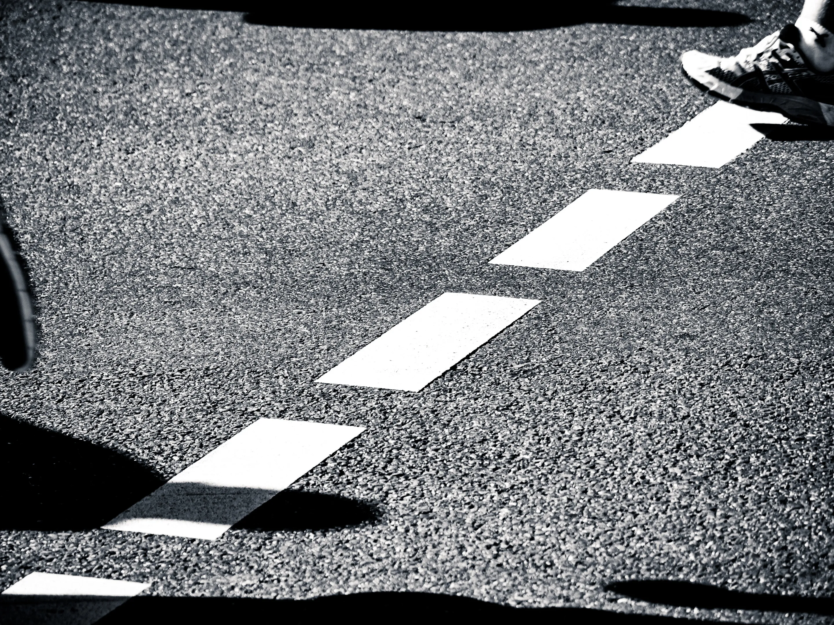 A pair of feet crossing a zebra crossing on a street.