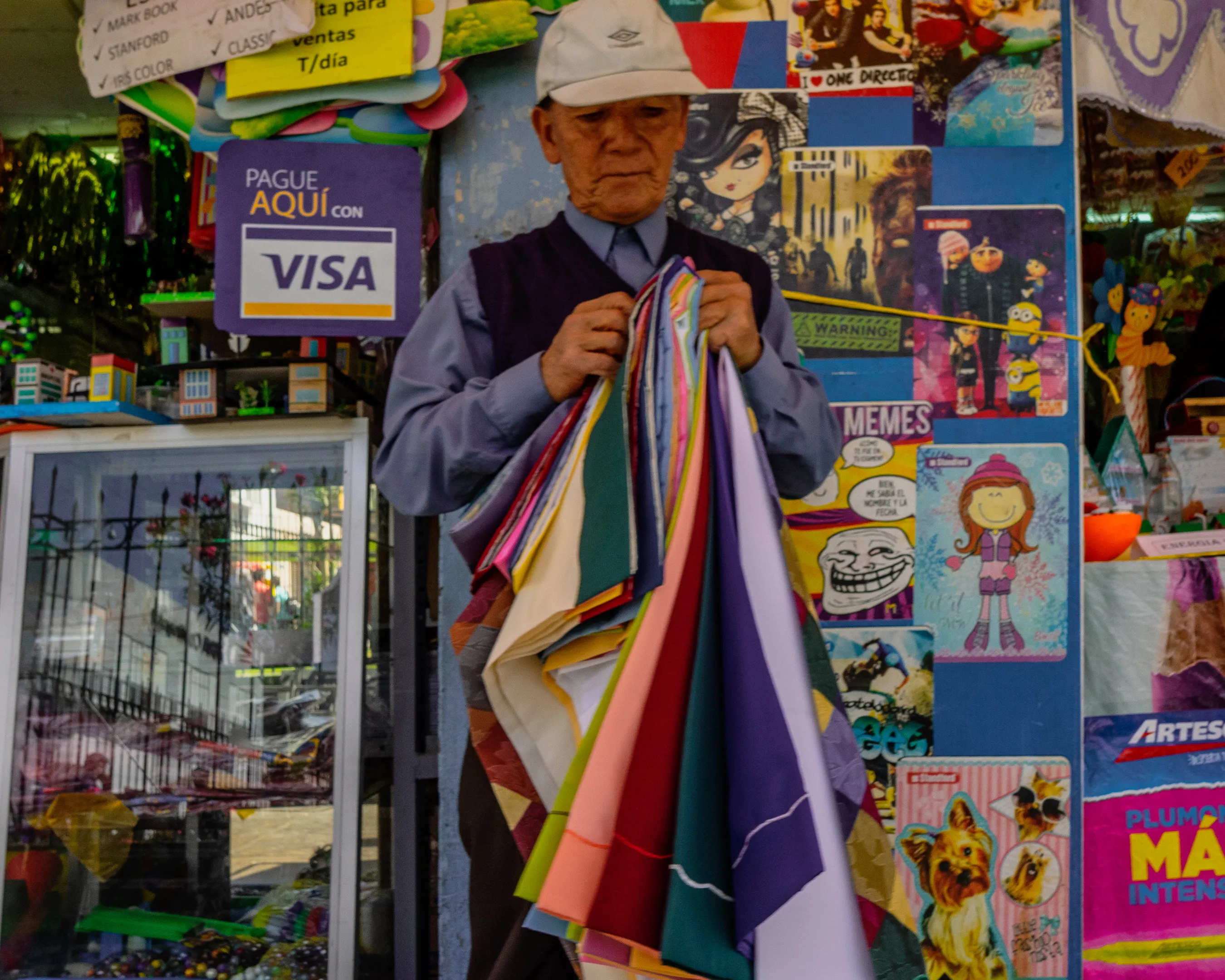 Man holding colorful fabrics in a store surrounded by posters and signs.