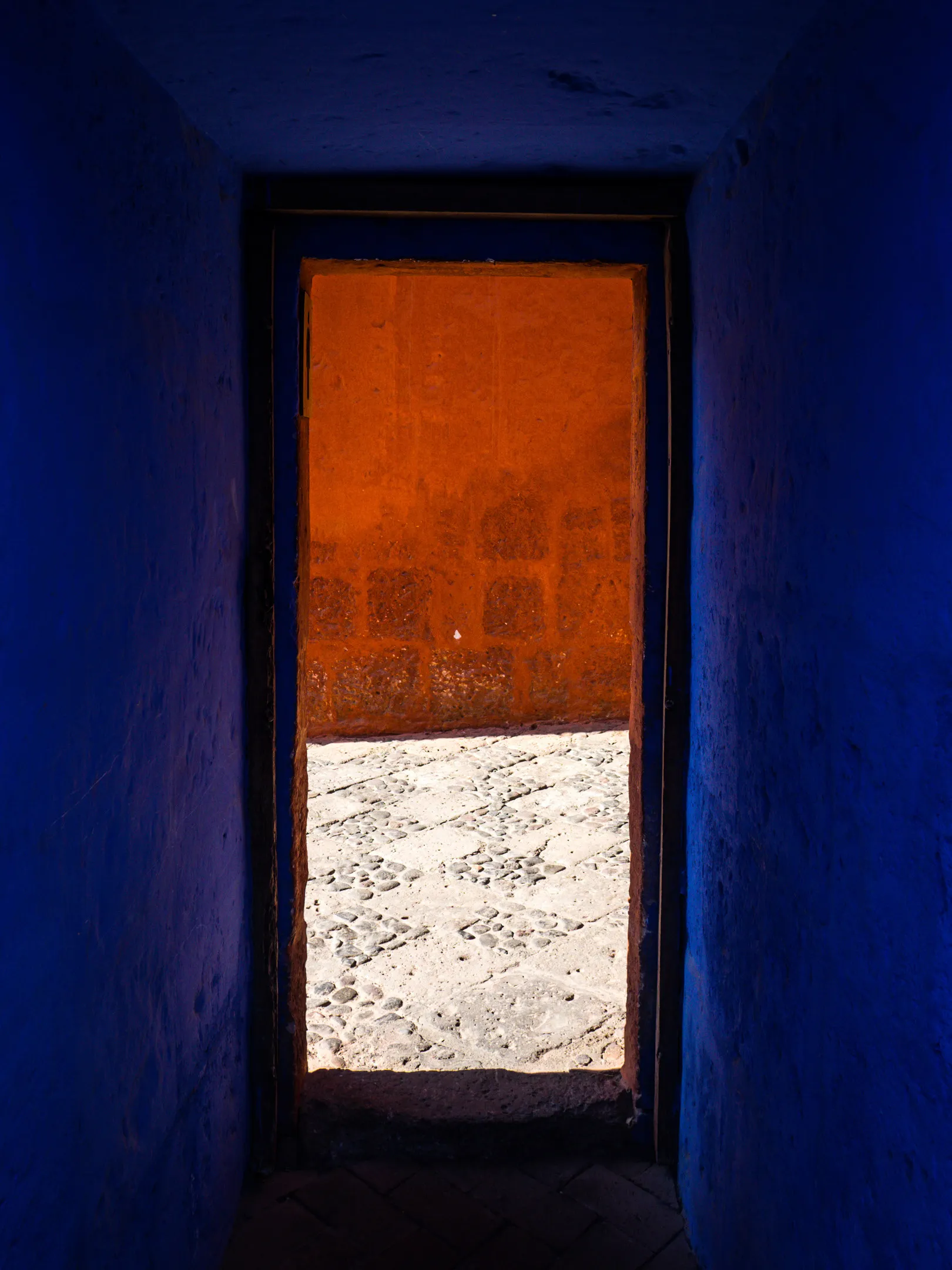 A bright, sunlit window framed in shadows on a blue wall with snow outside.