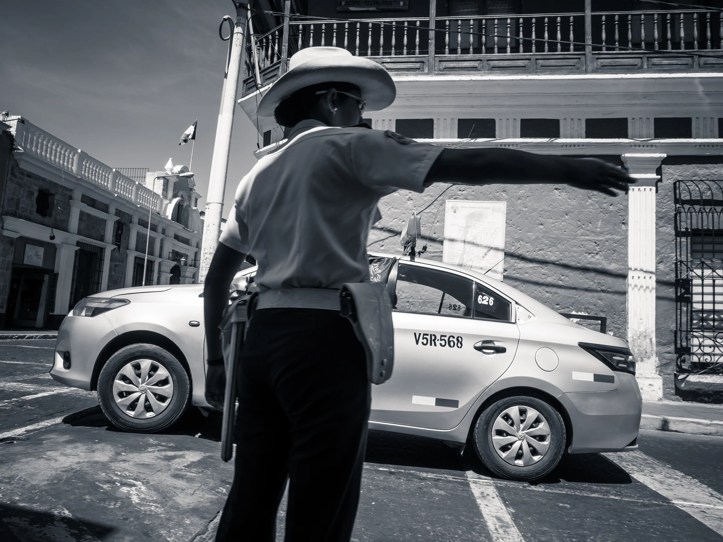 Traffic officer directing cars in urban setting with colonial architecture.