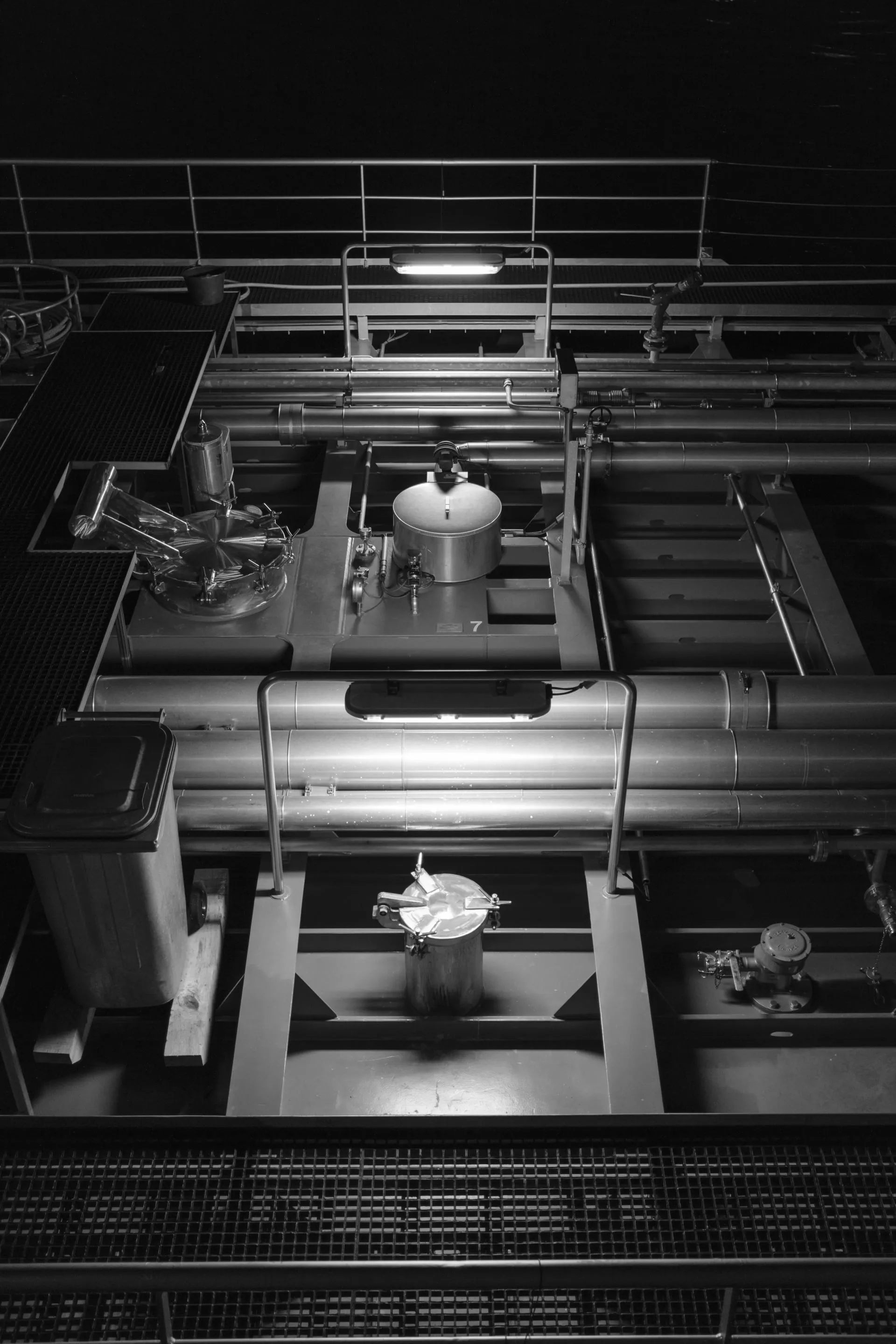 Industrial kitchen with stainless steel appliances, including ovens, grills, and storage units, under dim lighting.