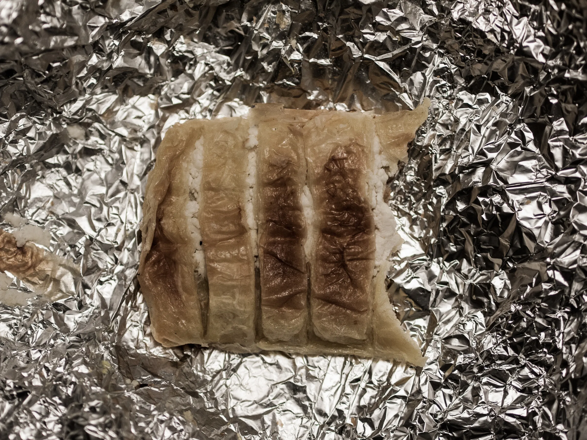 Grilled steak on crumpled aluminum foil, with grill marks visible.