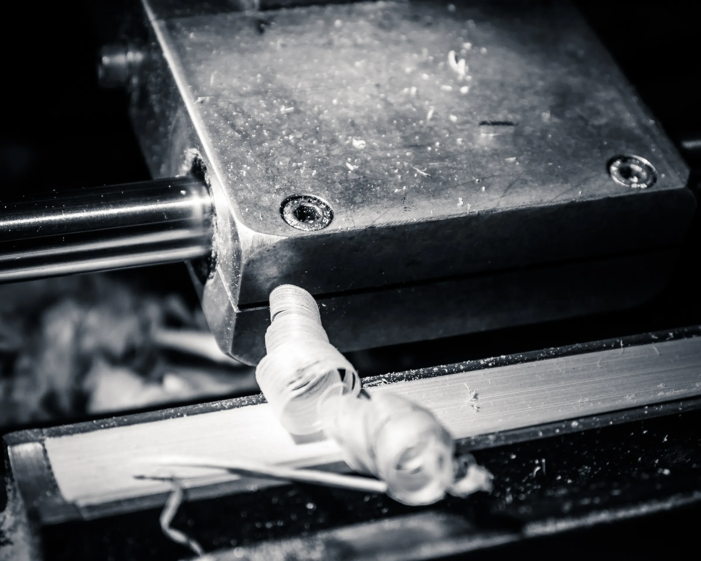 Hand in glove operating a machine with visible gears and bolts, black and white.
