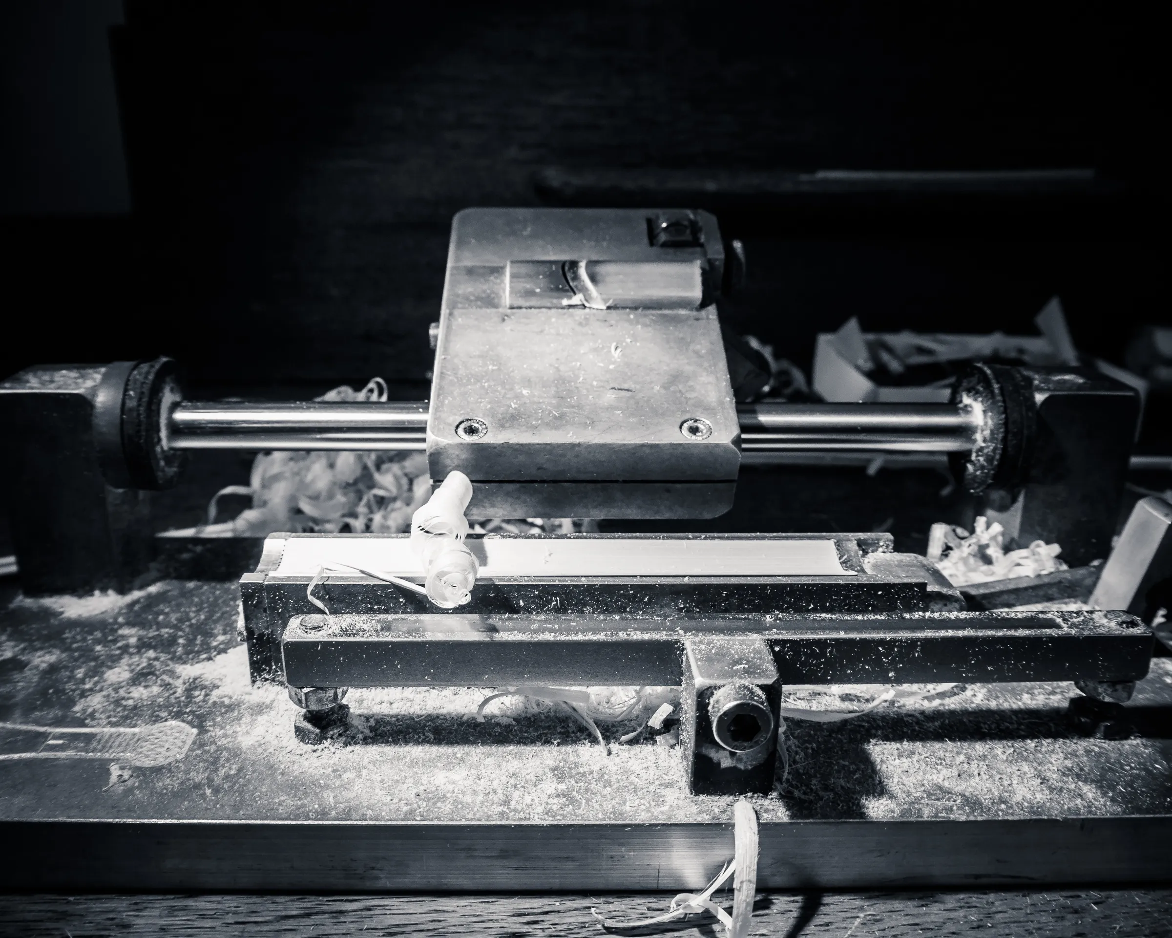 A vintage camera on a wooden workbench with scattered tools and debris, black and white.