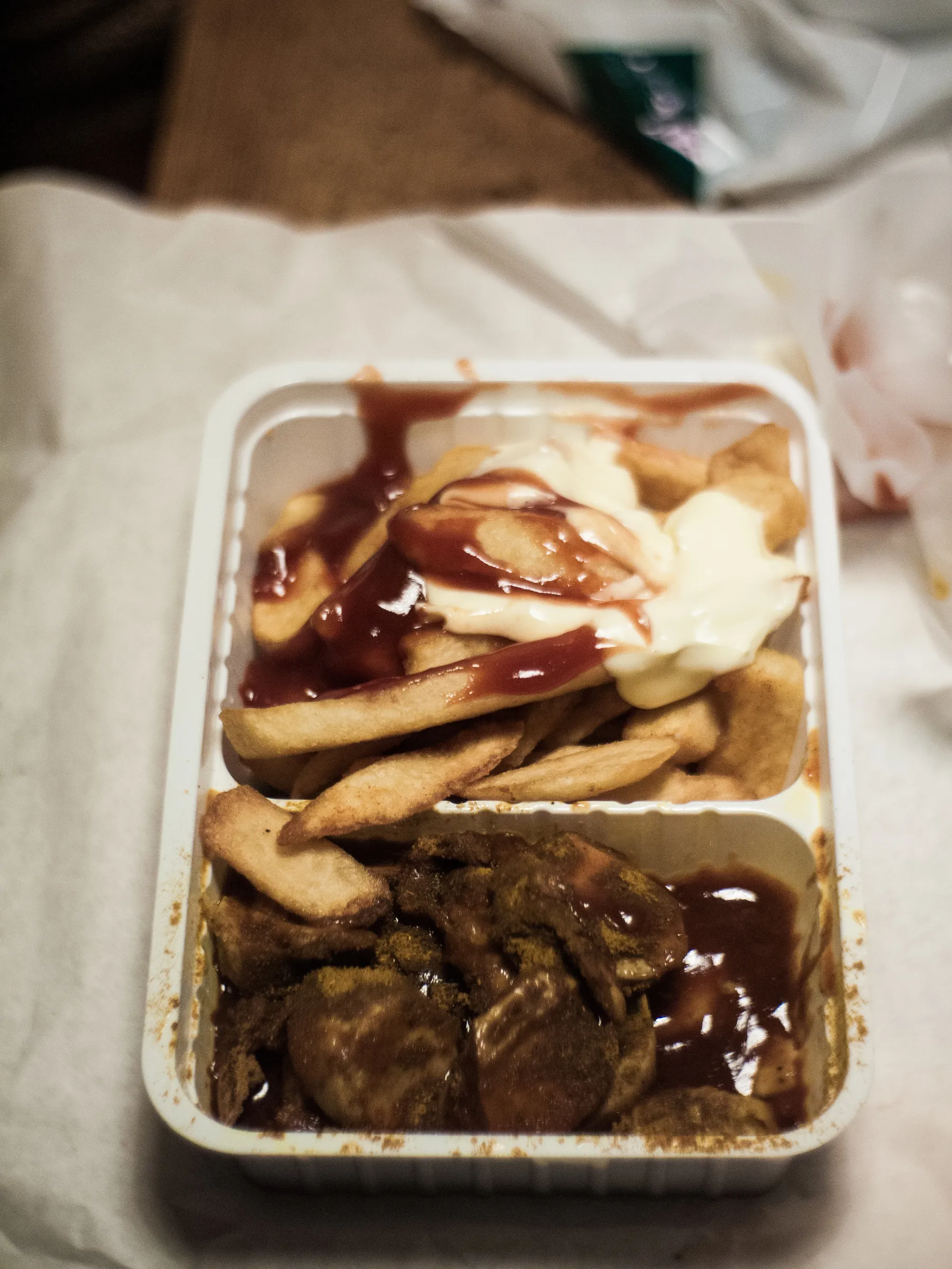Takeout container with fries, meatballs, ketchup, and mayonnaise.