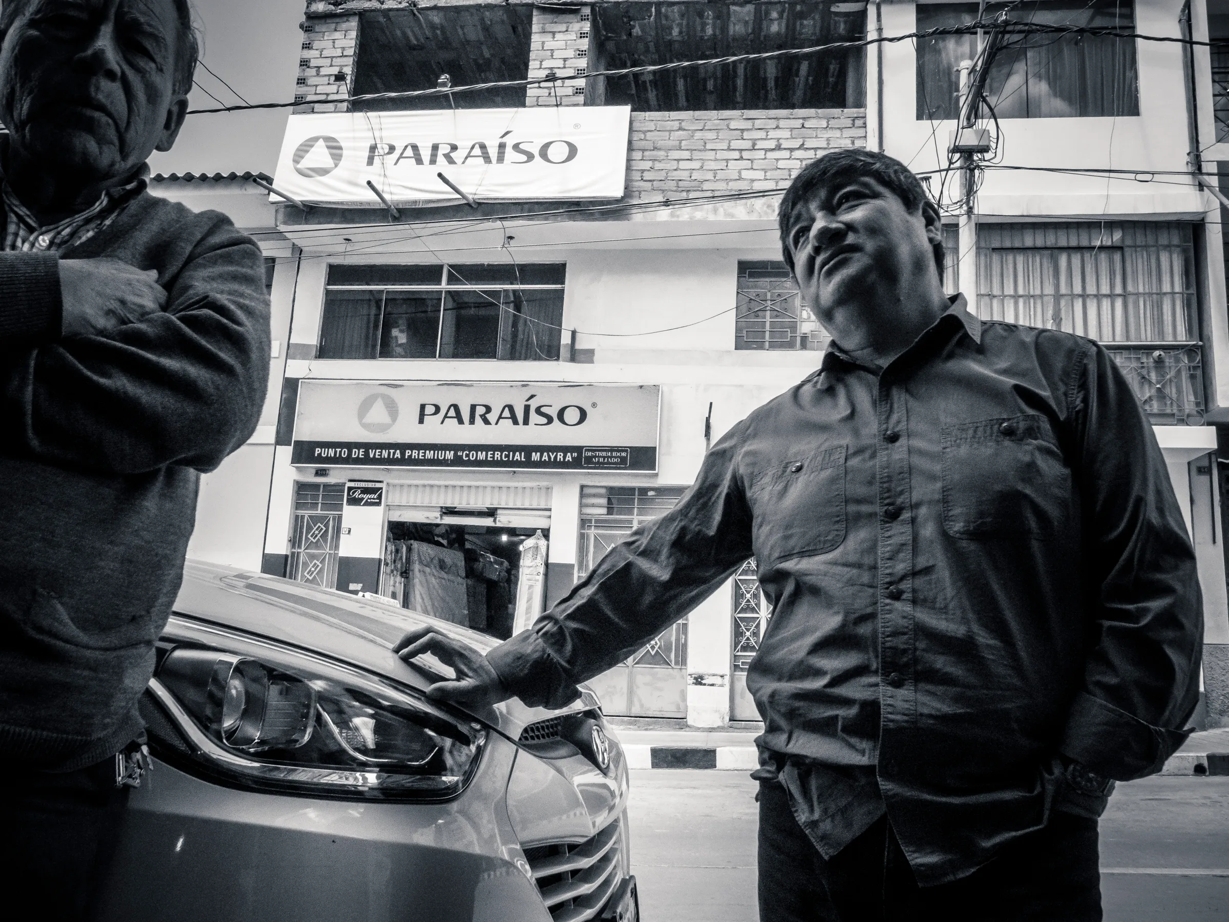 Two men beside a car outside the Paraíso store.