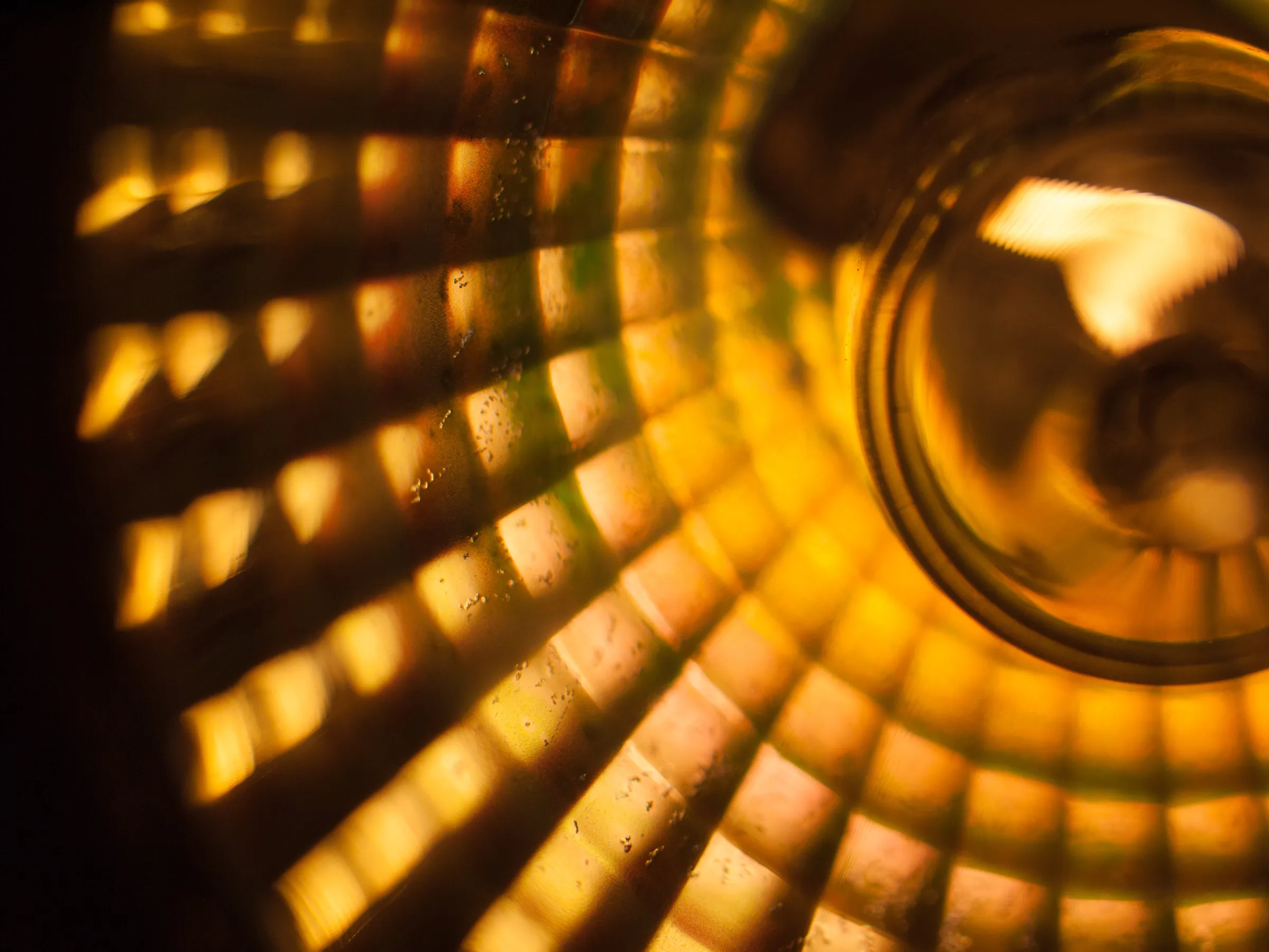 Warm, radiant light shining through a stained glass window with yellow and orange panels, casting a glow on a nearby surface.