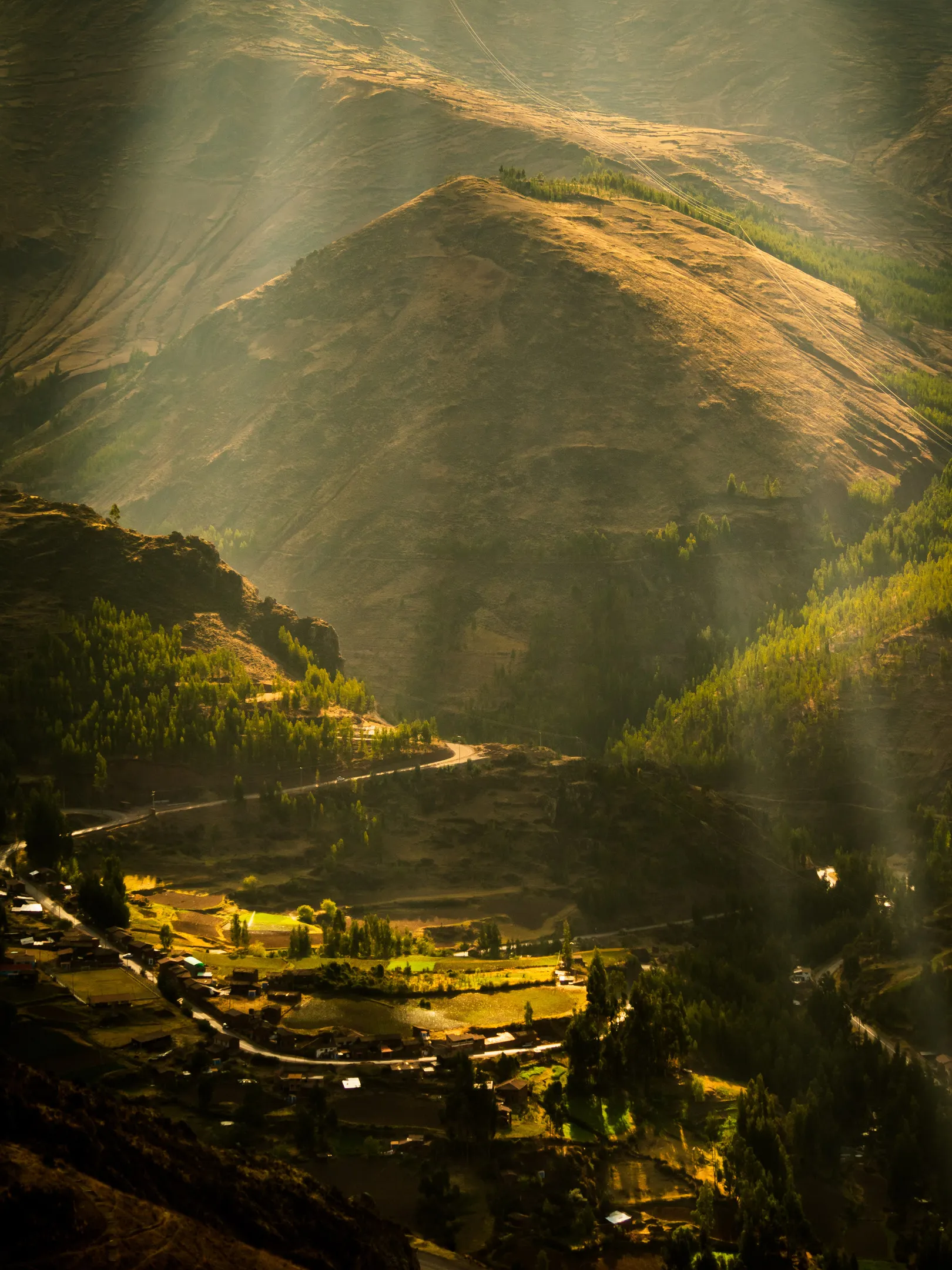 Sunlight on valley and mountainside with winding road.