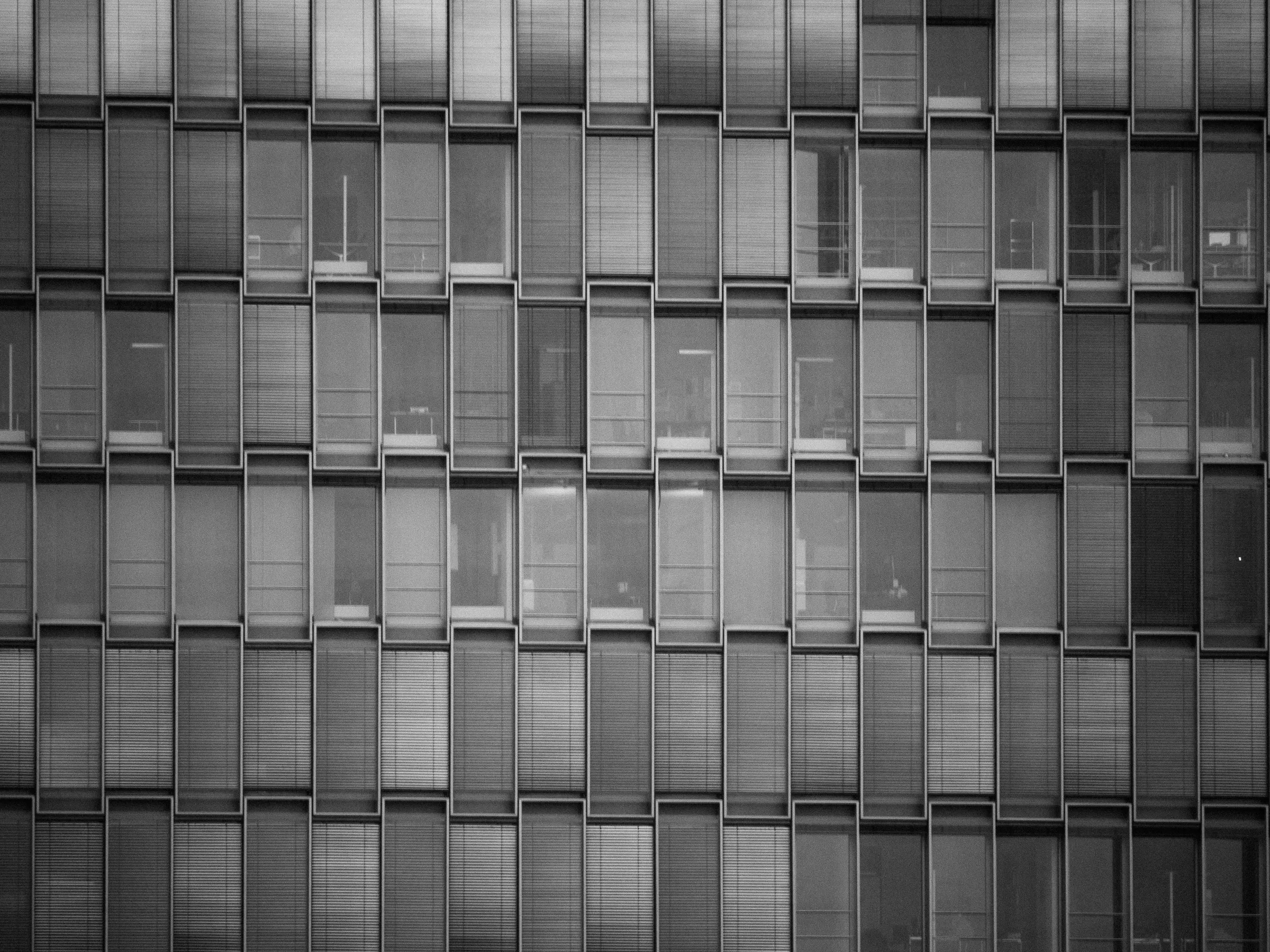 Grid of rectangular windows on a modern building facade, varying in shades of gray and black.