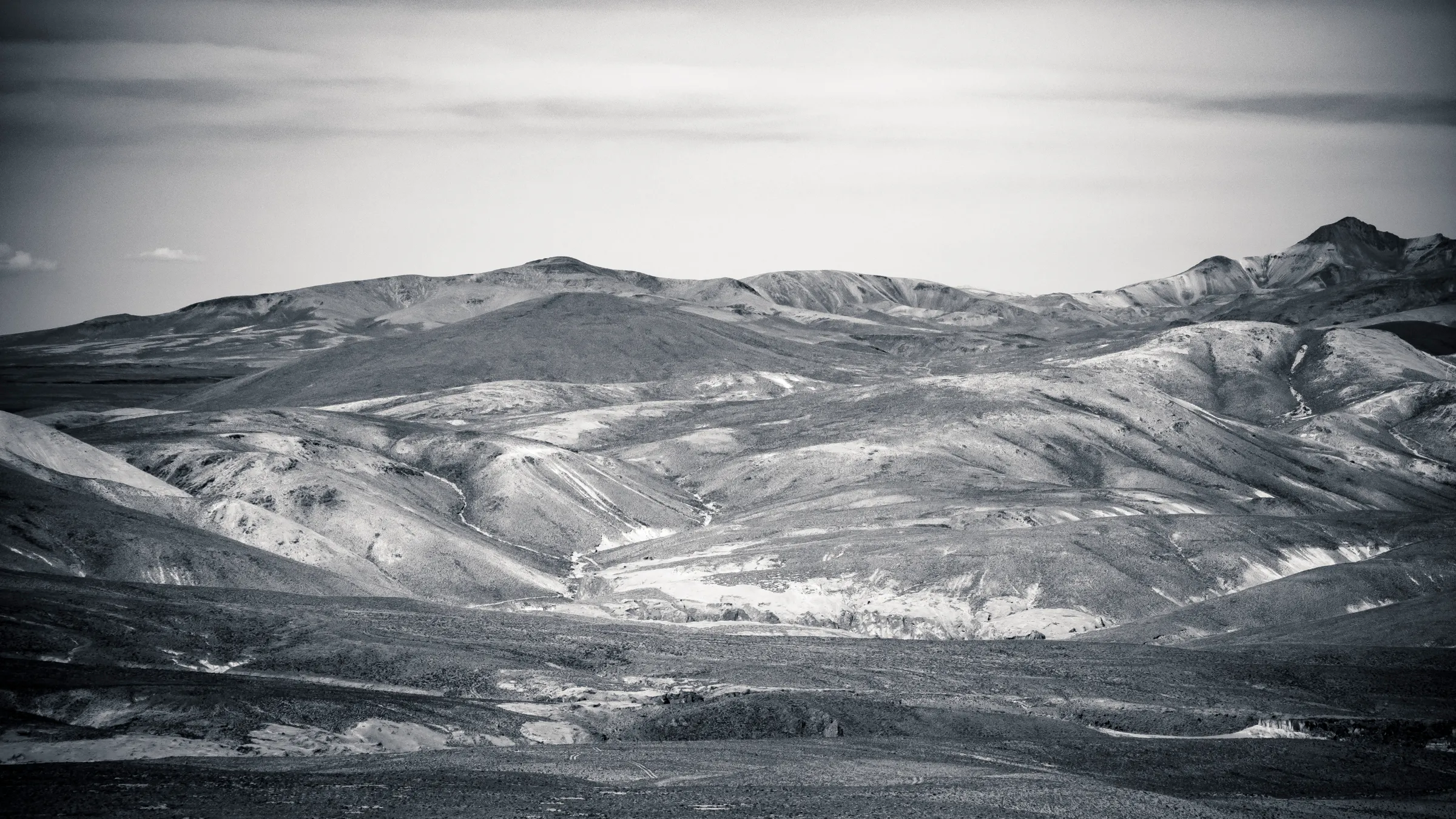 Rolling hills with valleys and sparse vegetation, black and white landscape photo.