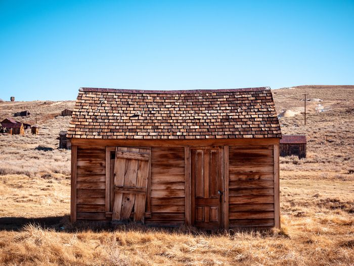 Abandoned wooden shed in arid landscape, rustic and weathered with a shingled roof.