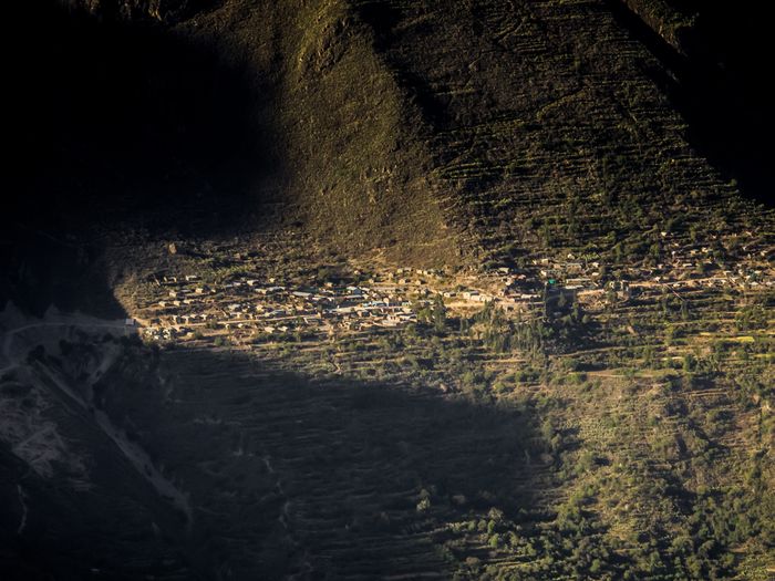 Aerial view of terraced fields at dusk, warm light on steps, dark silhouette of mountain in background.