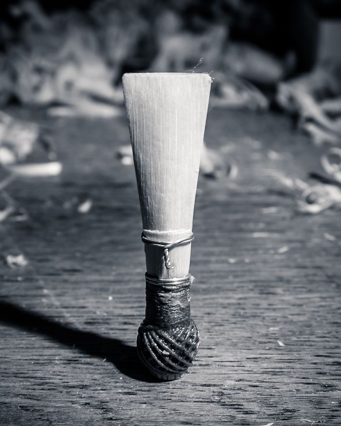 Bamboo stick with wrapped end, standing on weathered wooden surface.