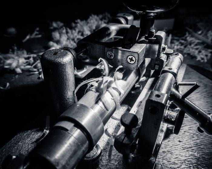 Close-up of an old rifle with a scope, showing detailed parts and worn wooden stock.