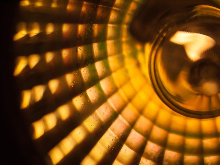 Warm, radiant light shining through a stained glass window with yellow and orange panels, casting a glow on a nearby surface.