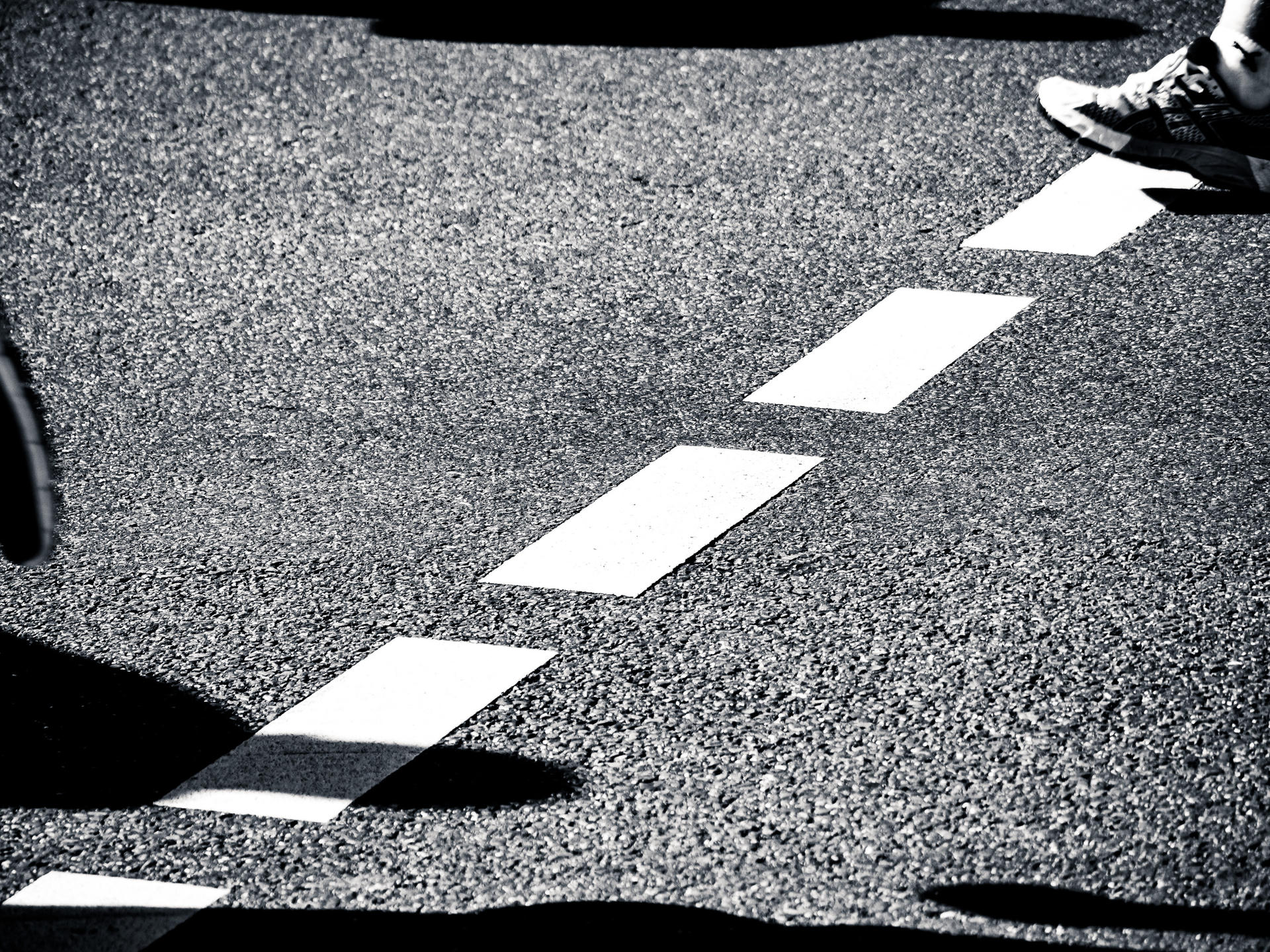 A pair of feet crossing a zebra crossing on a street.