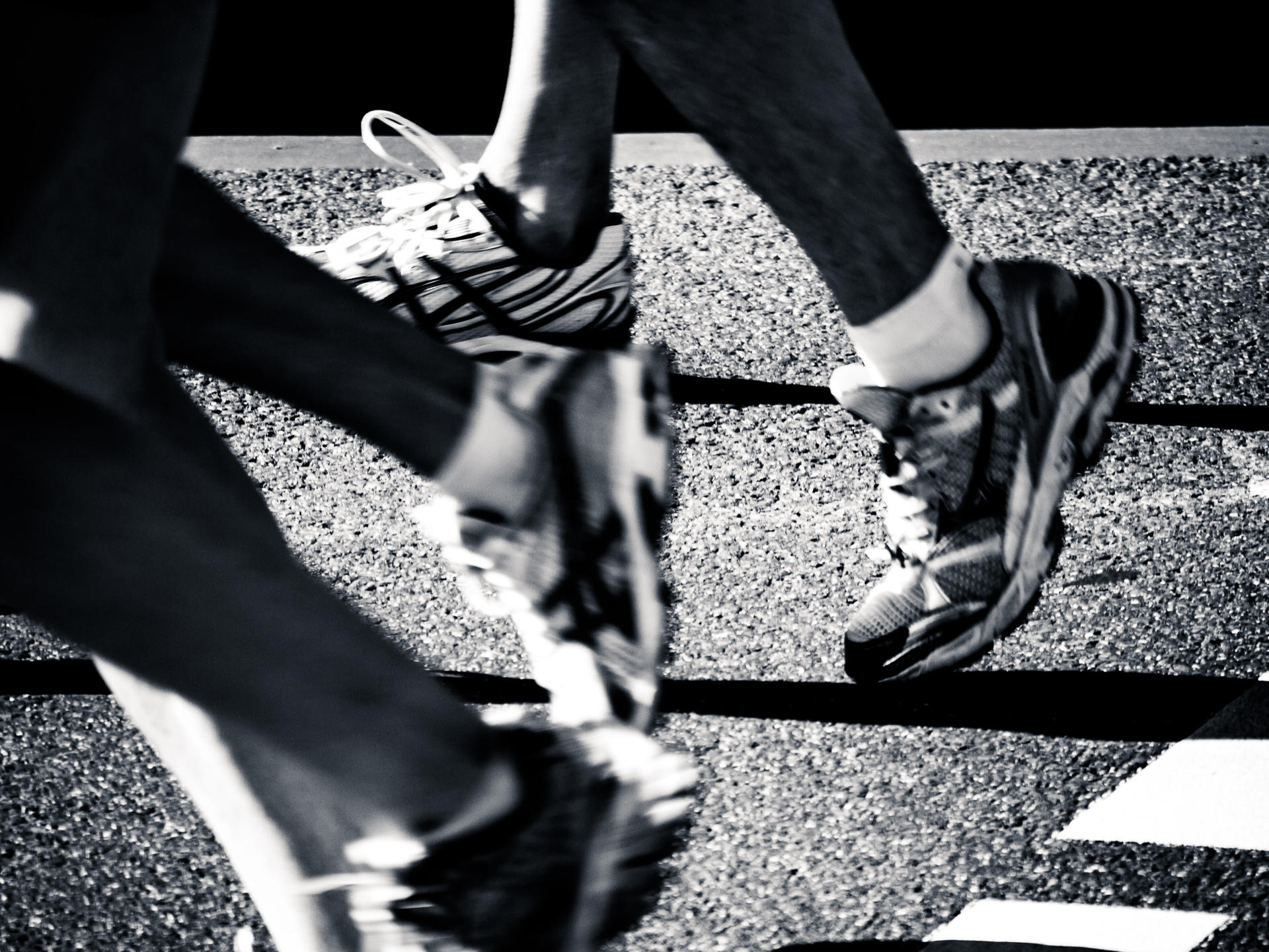 Two people crossing a street, feet in motion on a crosswalk grid.
