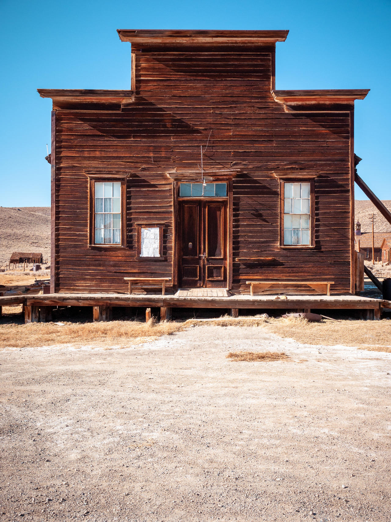 Rustic wooden building with two windows and a door, set in a barren landscape.