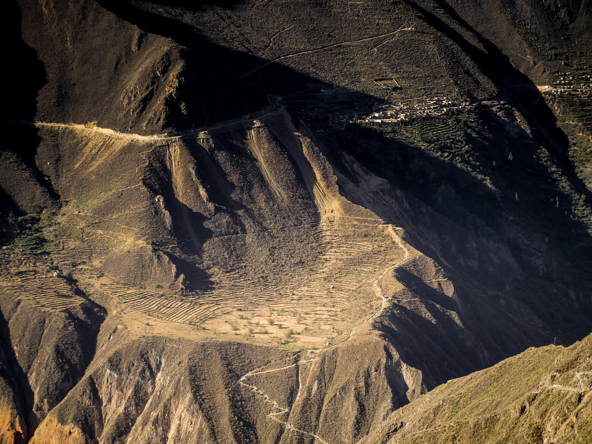Terraced hillsides in a mountainous region, with paths winding through the landscape.