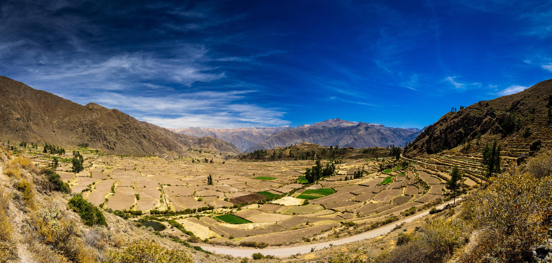 Vast mountain landscape with terraced fields and a clear blue sky.