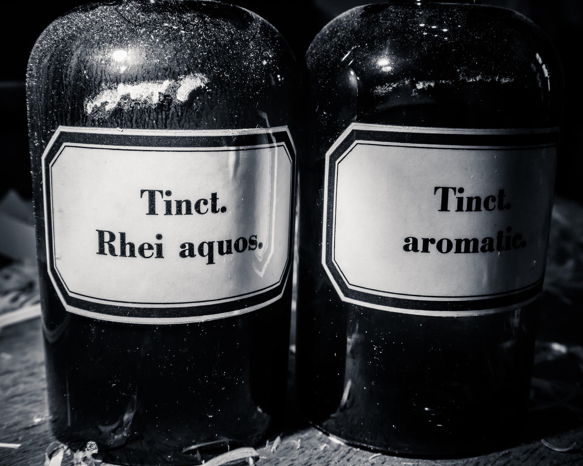 Two black bottles with white labels reading "Tinct. Rhei aquos." and "Tinct. aromatic."