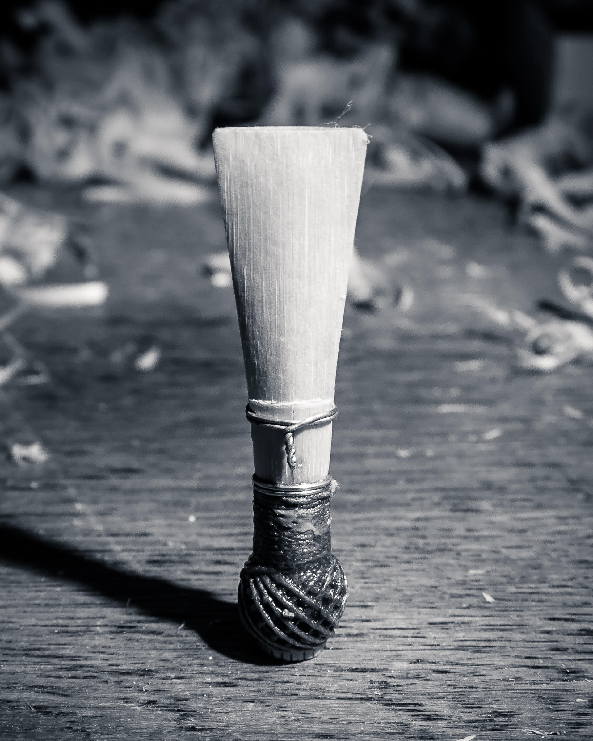 Bamboo stick with wrapped end, standing on weathered wooden surface.