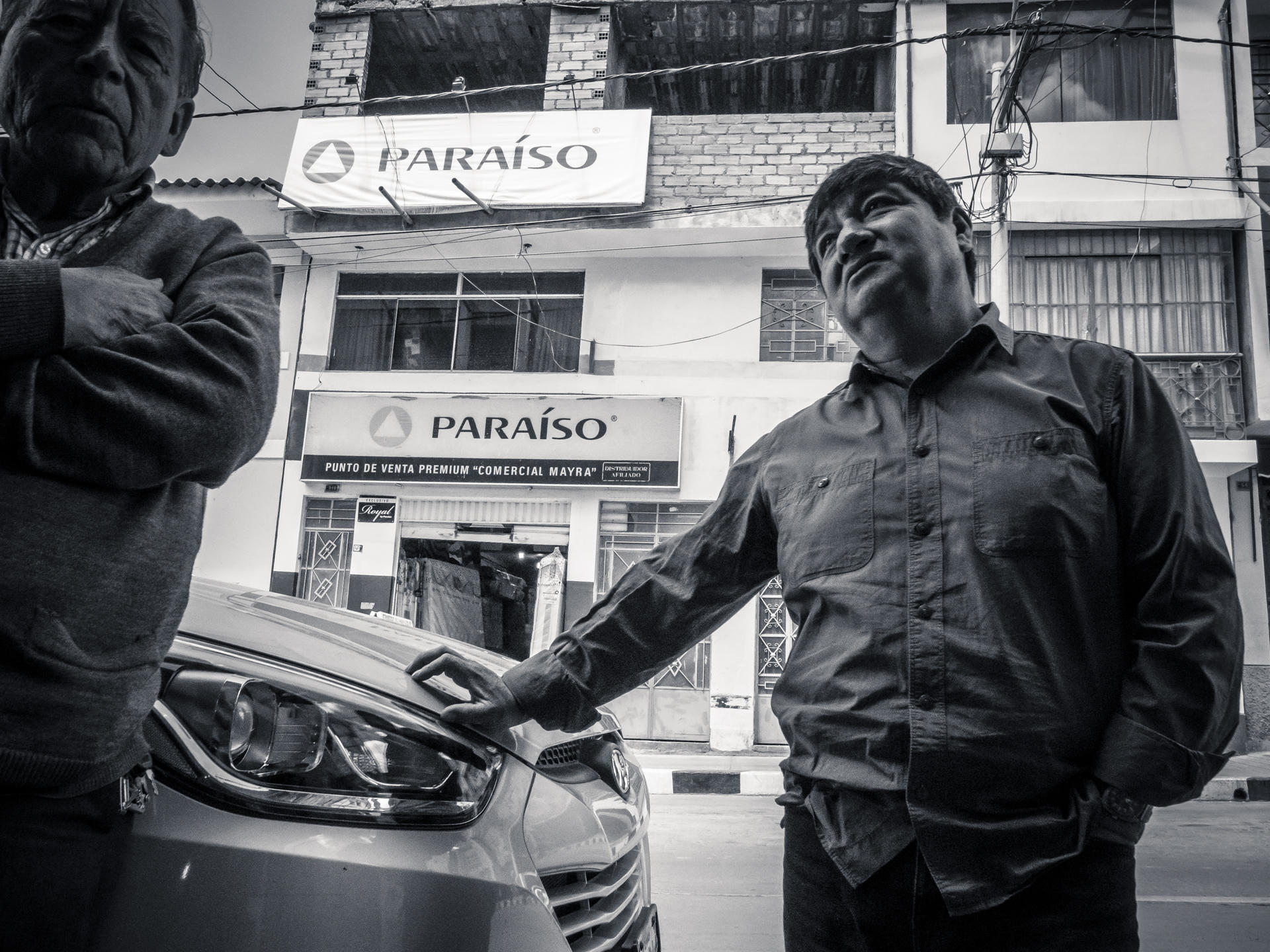 Two men beside a car outside the Paraíso store.