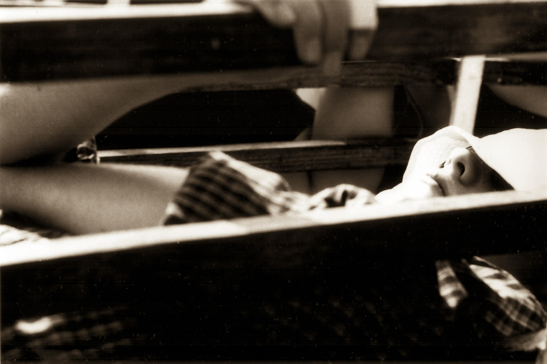 A baby lying in a crib with striped blanket, viewed from above.