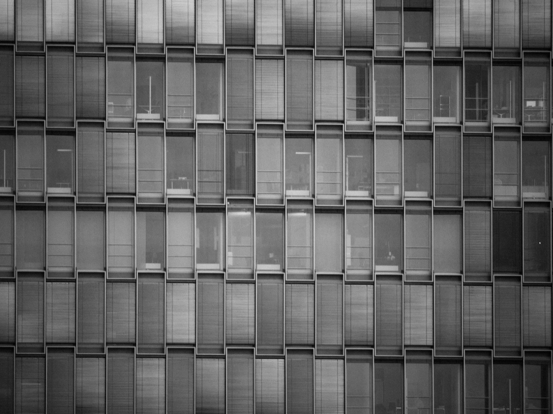Grid of rectangular windows on a modern building facade, varying in shades of gray and black.